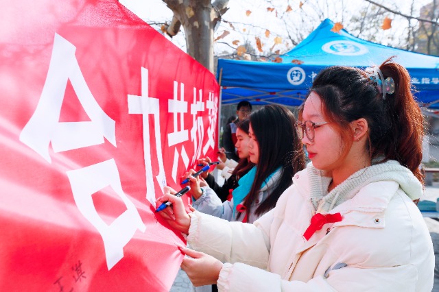 20231127中國石油大學(xué)（華東）青年學(xué)子在合力共抗艾滋的條幅上簽字，表達(dá)抗擊艾滋病的決心和信心  .jpg